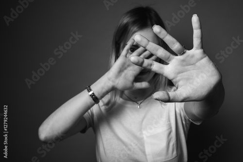 Obraz na płótnie black and white photo, young woman in white t-shirt covering face with hands, emotion stress, insecurity. Concept of fear, privacy, rejection or social anxiety w salonie