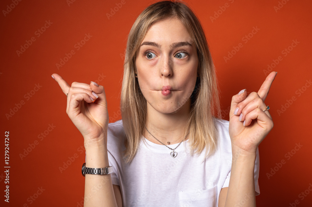 Portrait of a funny young, emotional girl making a fish face, lips and pointing with both hands. Playful facial expression, silly pose and bright orange background. Humor and fun concept Portrait of a funny young, emotional girl making a fish face, lips and pointing with both hands. Playful facial expression, silly pose and bright orange background. Humor and fun concept