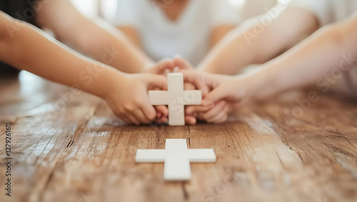 Children's hands holding a wooden cross on a table, symbolizing faith, family, and unity; ideal for religious websites, brochures, or social media