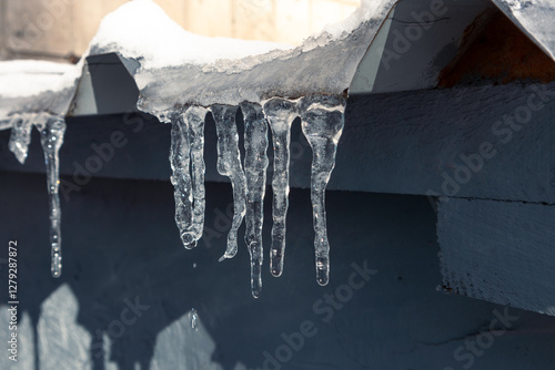 фотографія Small melting icicles hang from the roof of the building
