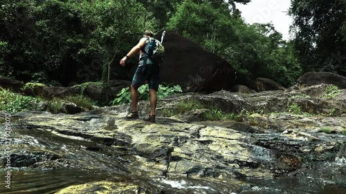 A tourist walks along a stone plateau, crossing a stream and comes to a giant stone