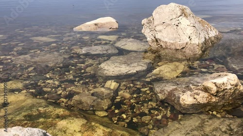 A large stone near the river bank. The transparent surface of the water.