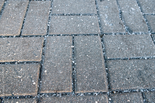 Obraz na płótnie Salt crystals on paving stone slabs in winter, surface treatment methods for preventing ice buildup and slippery hazards. Paving slabs with visible salt crystals in winter season w salonie