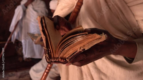 Priest reads and sings verses from historic Amharic Bible book inside rock-hewn Church of Saint George in Lalibela, ancient civilization and peaceful atmosphere in Ethiopia Africa
