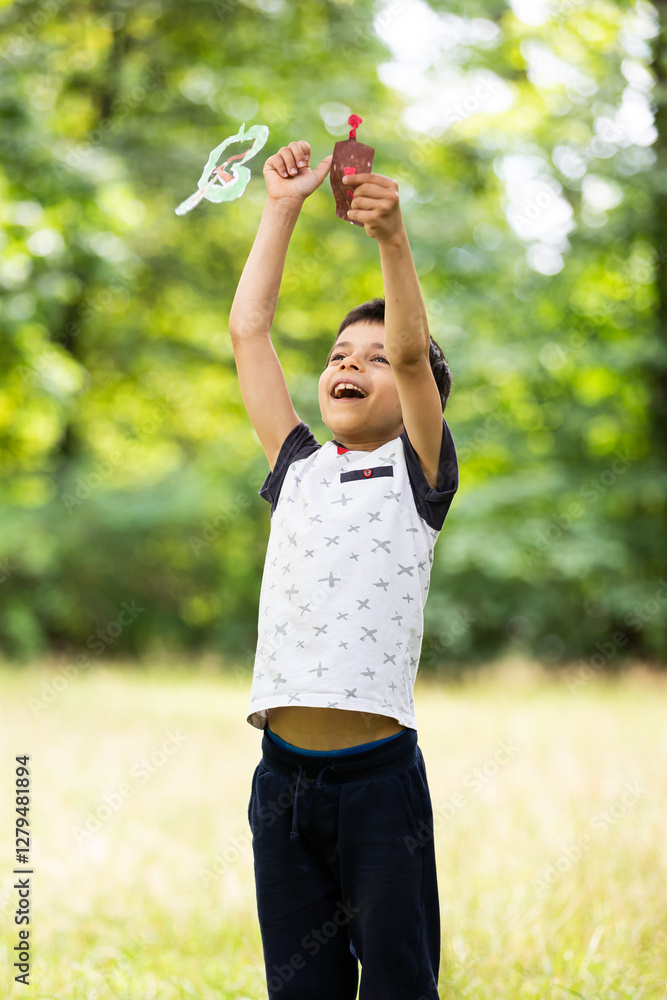 Little adorable boy paying with handmade drone in park