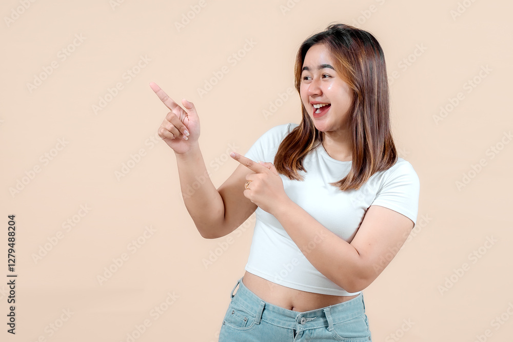 A joyful young woman smiling and playfully pointing in different directions, set against a soft beige background, radiating enthusiasm and positivity. A joyful young woman smiling and playfully pointing in different directions, set against a soft beige background, radiating enthusiasm and positivity.