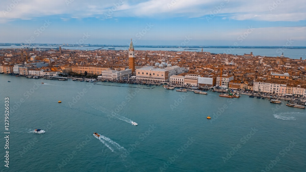 Fototapeta premium Venetian Panorama: A stunning aerial view captures the beauty of Venice, showcasing its iconic architecture, winding waterways, and vibrant cityscape under a soft, inviting sky.