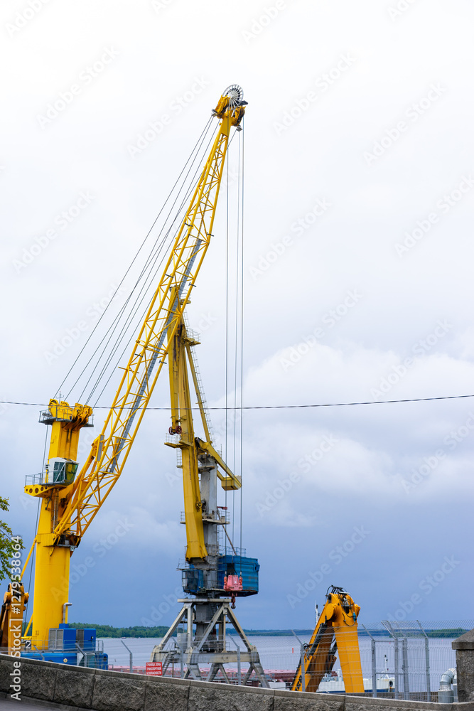 port cranes, industrial harbor cranes for sea port with a stabilizer and a hook against a blue sky. High quality photo port cranes, industrial harbor cranes for sea port with a stabilizer and a hook against a blue sky. High quality photo