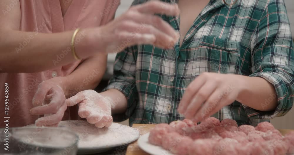 A mother and daughter are collaborating in the kitchen, preparing meatballs. They then place them on a plate.
Traveling in: A mother and daughter are collaborating in the kitchen, preparing meatballs. They then place them on a plate.
Traveling in: