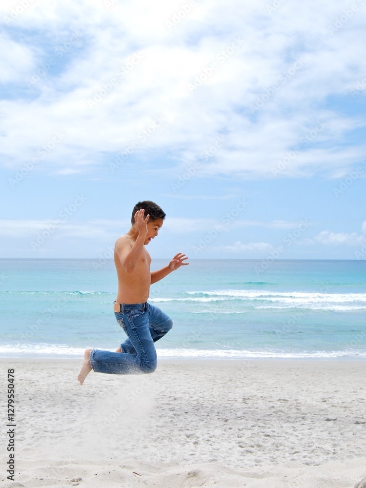 Barefoot shirtless boy in jeans jumping in the air on a beach, Carmel-by-the-Sea, California, USA Barefoot shirtless boy in jeans jumping in the air on a beach, Carmel-by-the-Sea, California, USA