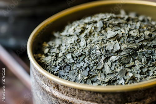 Close-up of premium dried gyokuro sencha tea leaves in a tin container, ideal for promoting quality tea products photo