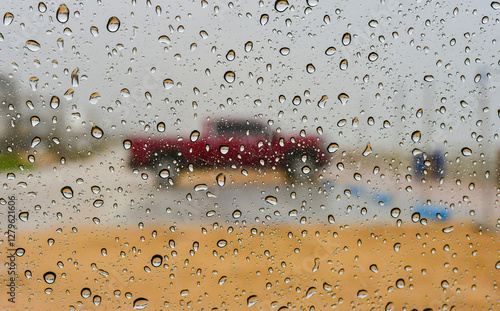 Raindrops on the glass, car in the center of the frame.