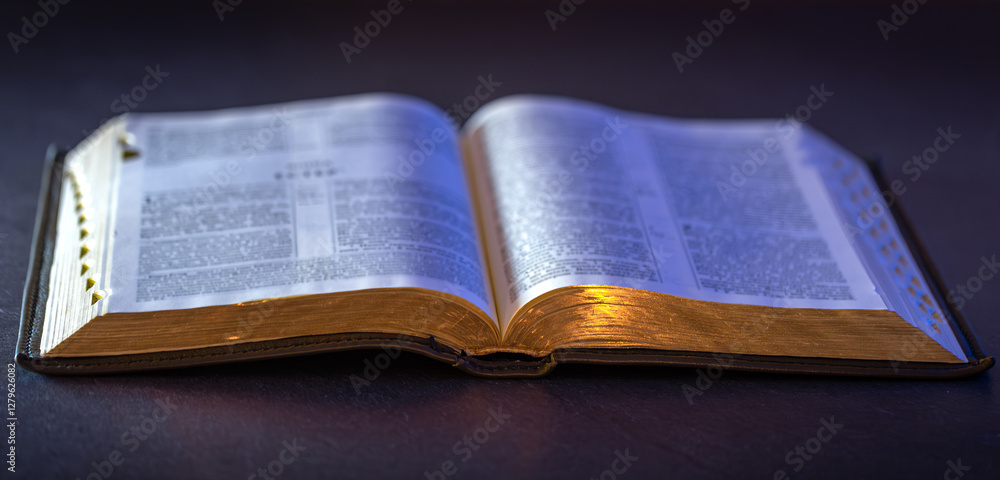 Fototapeta premium Open Holy Bible on the table. Religion concept. Bible on black background.
