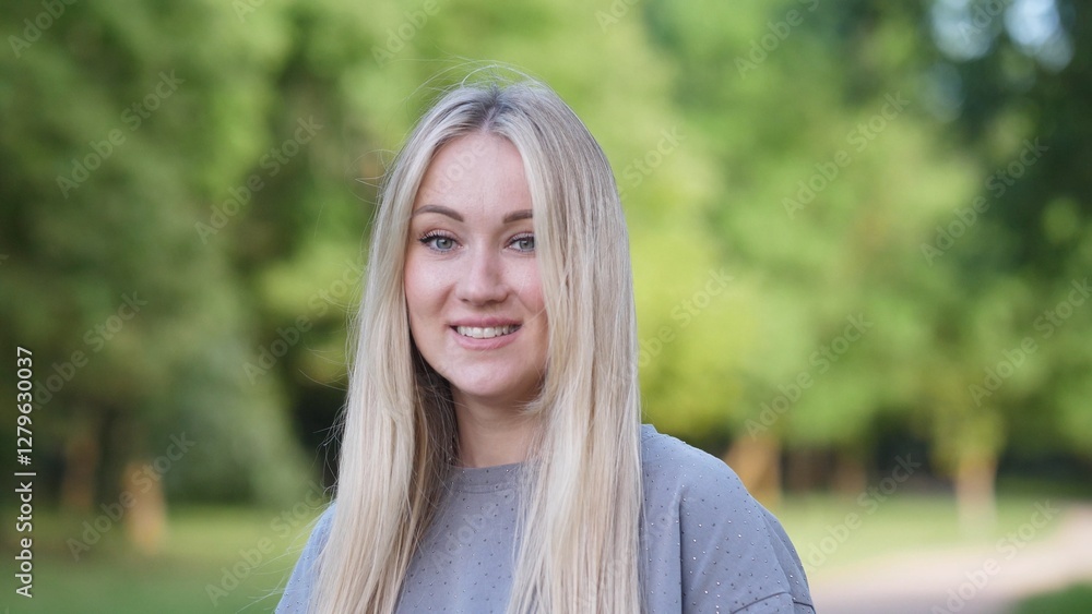 A cheerful young woman with flowing hair is posing joyfully in a vibrant and lush green park, radiating happiness A cheerful young woman with flowing hair is posing joyfully in a vibrant and lush green park, radiating happiness