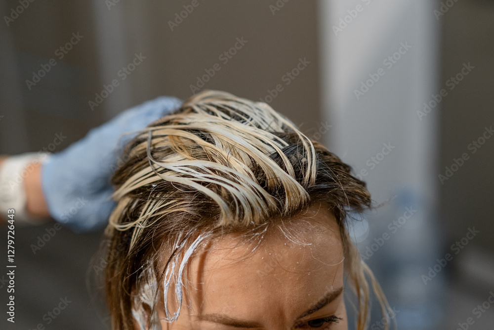 Naklejka premium Hair coloring process with a stylist applying bleach to a clients roots in a modern salon setting
