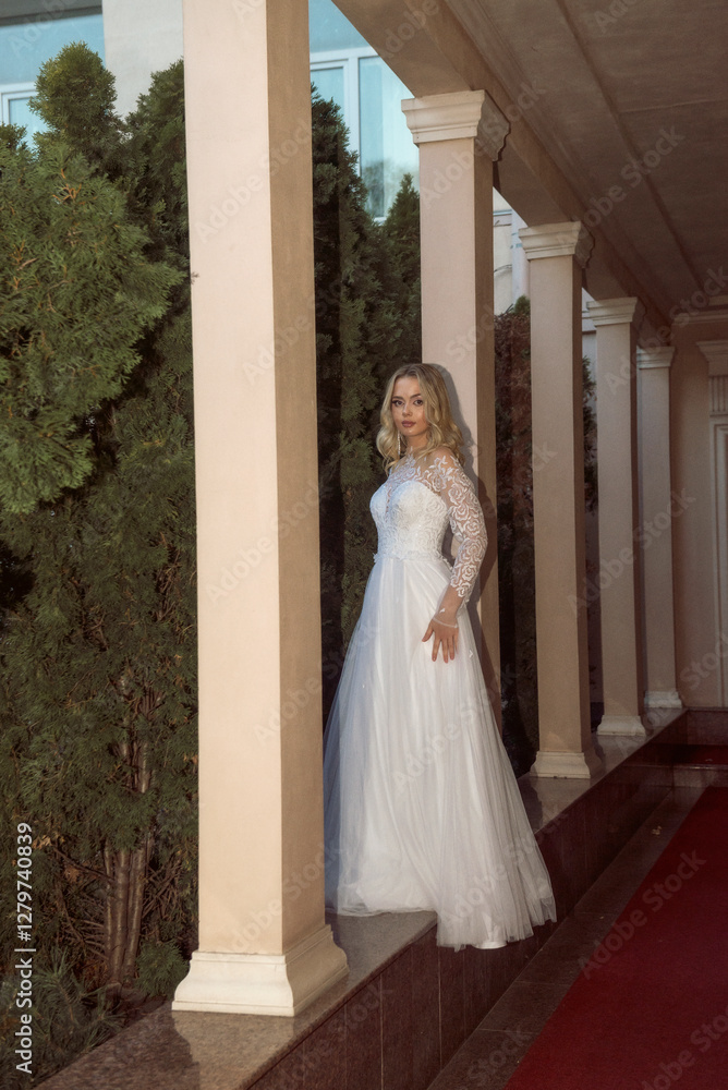 Obraz premium beautiful blonde bride posing in open gallery of hotel. in long wedding dress