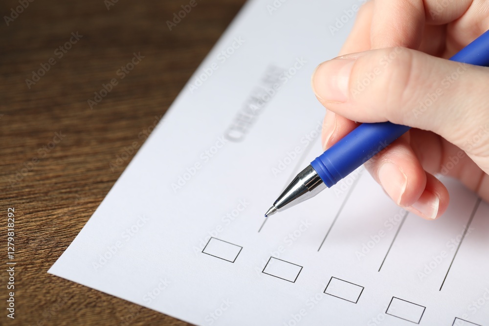 Woman checking box of paper form at wooden table, closeup Woman checking box of paper form at wooden table, closeup