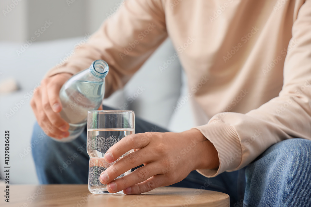 Young man pouring water into glass at home, closeup Young man pouring water into glass at home, closeup