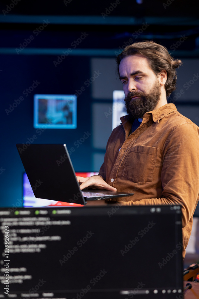 Computer scientist walking in apartment designing and developing software applications using laptop. IT professional standing in living room, implementing and maintaining company systems Computer scientist walking in apartment designing and developing software applications using laptop. IT professional standing in living room, implementing and maintaining company systems