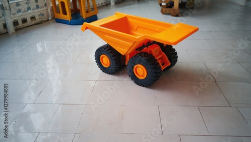 Orange toy dump truck indoors, playroom background photo