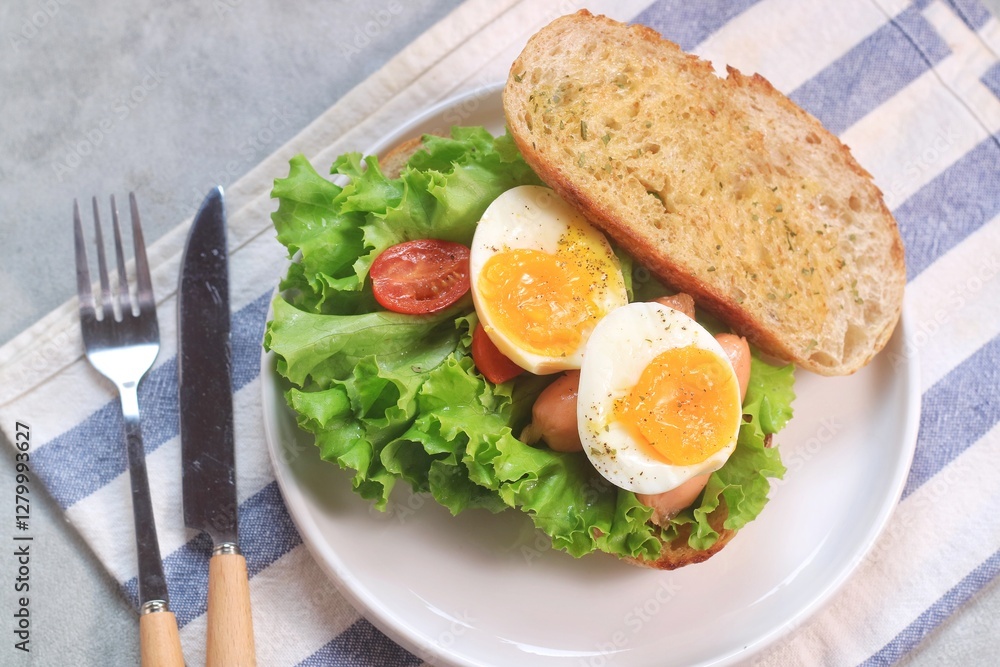 Sourdough bread open faced sandwiches with lettuce, tomatoes, egg and sausage. A healthy and delicious breakfast.
