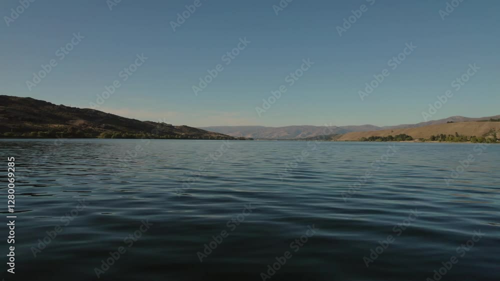Serene lake view in Cromwell with calm waters, distant hills, and clear blue sky Serene lake view in Cromwell with calm waters, distant hills, and clear blue sky