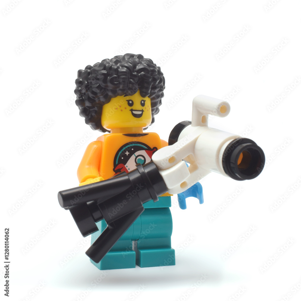 Naklejka premium Lego minifigure of smily astronomer with telescope isolated on white. Editorial illustrative image of collectable toys of edition 27.