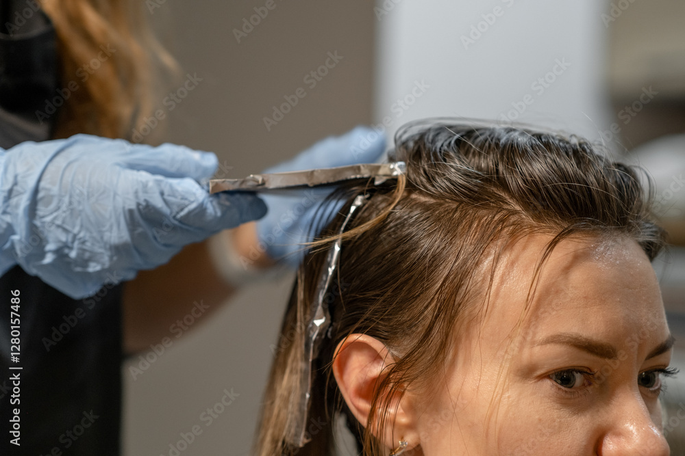 Fototapeta premium Hair coloring process with highlights in a modern salon setting during a bright afternoon