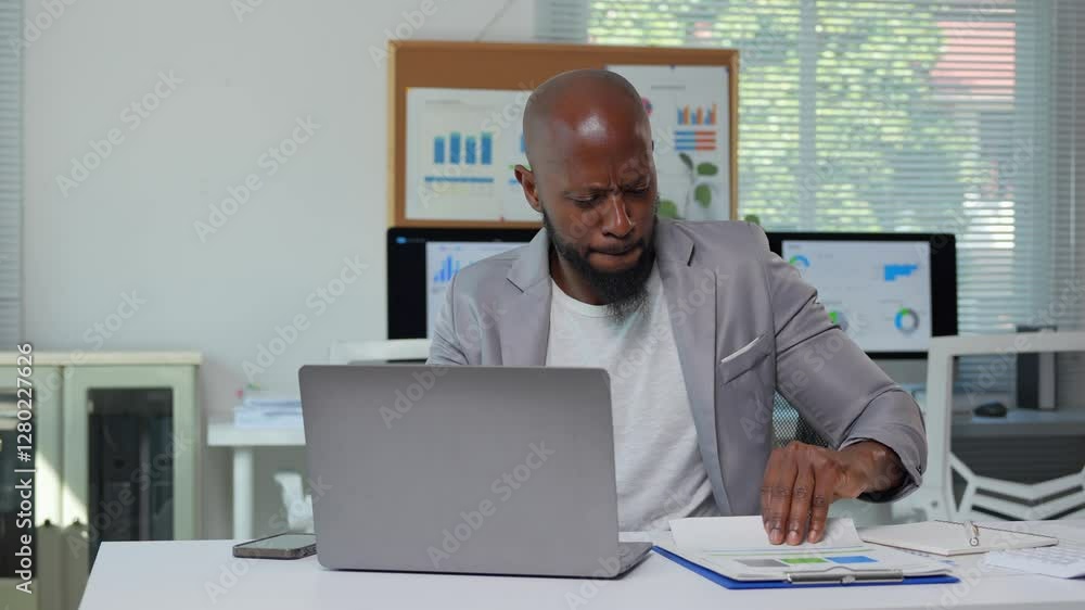 Professional business executive experiencing growing stress while reviewing financial reports. Displaying increasing frustration and anxiety during challenging work moment in corporate office setting Professional business executive experiencing growing stress while reviewing financial reports. Displaying increasing frustration and anxiety during challenging work moment in corporate office setting