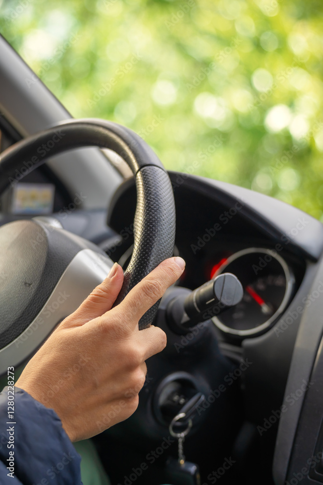 Naklejka premium Lady hand holding steering wheel of car while driving.
