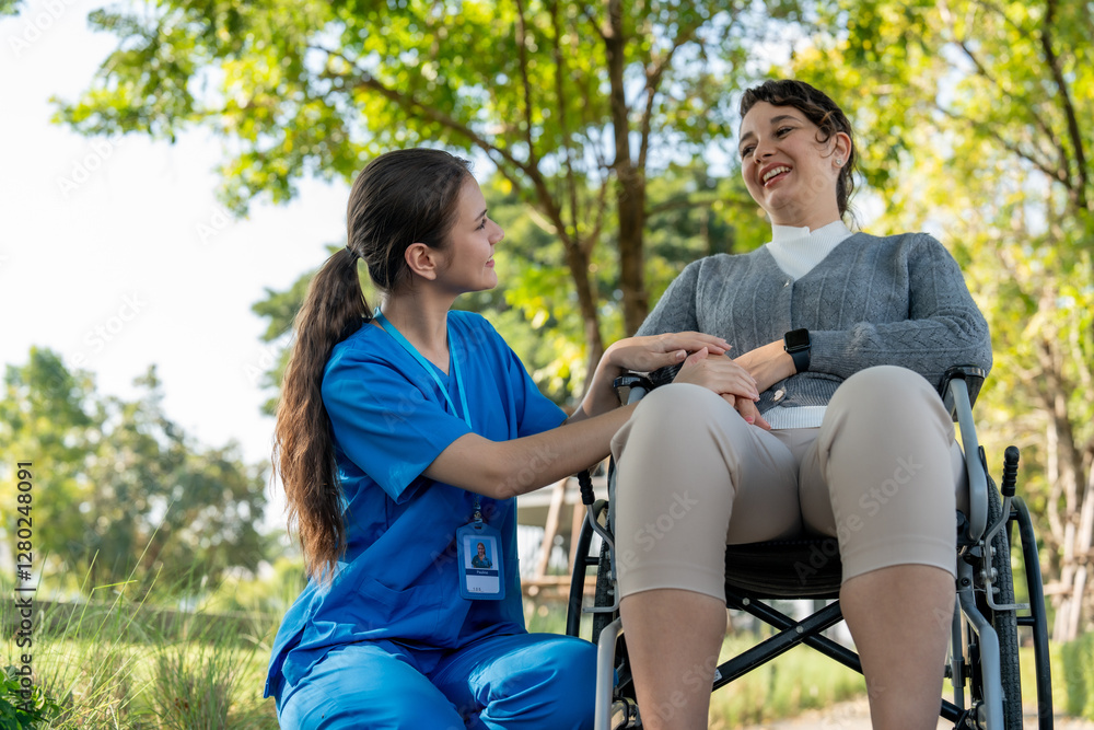 caregiver in blue scrubs interacts warmly with woman in wheelchair, both smiling in sunny outdoor setting. scene conveys compassion and support caregiver in blue scrubs interacts warmly with woman in wheelchair, both smiling in sunny outdoor setting. scene conveys compassion and support