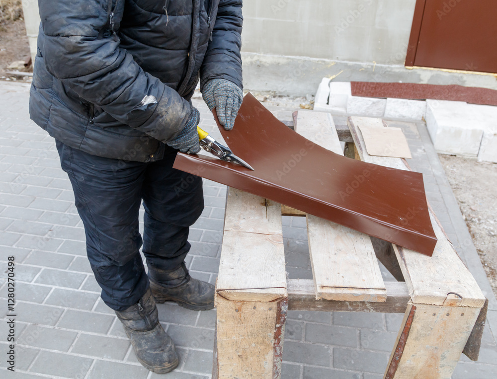 A man is cutting a piece of wood with a pair of scissors