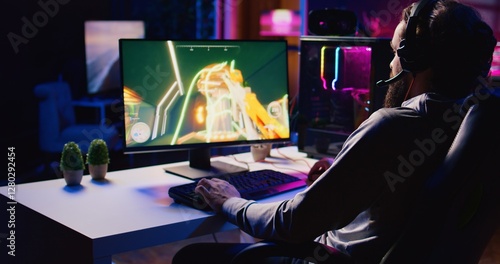 Fotografia Man relaxing by playing science fiction FPS videogame with friends on PC at computer desk late at night