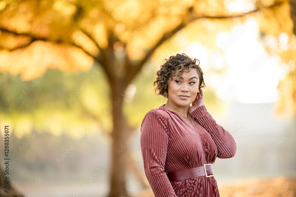 Stylish woman posing confidently in a park with golden autumn foliage Stylish woman posing confidently in a park with golden autumn foliage