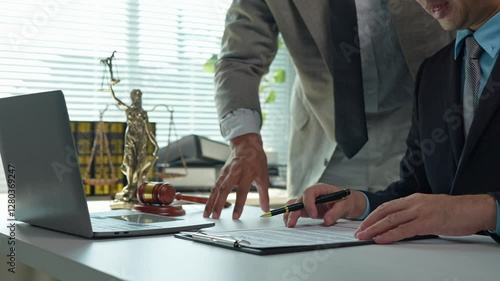 Legal professionals collaborate on a contract, carefully reviewing terms and conditions before signing, demonstrating expertise and attention to detail in a formal office setting