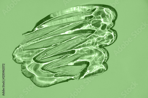 Transparent cream gel texture with bubbles on a green background.