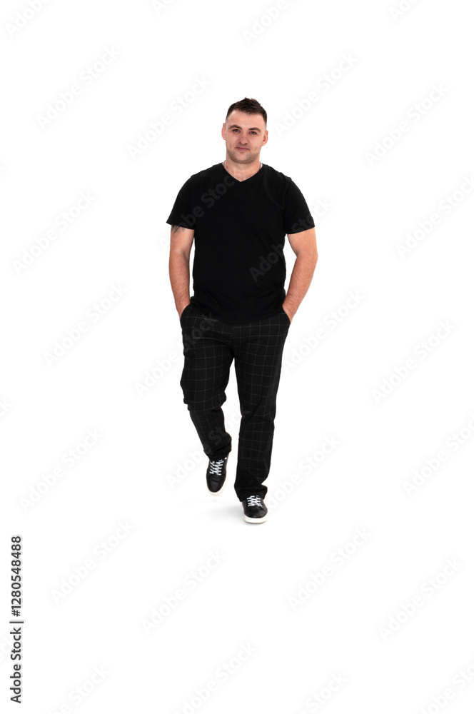 Fototapeta premium A handsome dark-haired man in a black T-shirt, trousers and sneakers on a white background