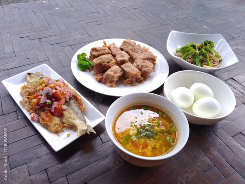 spicy fried fish, fried tofu and boiled egg on wooden table