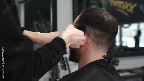 Skilled barber trimming client's hair using electric razor, creating contemporary hairstyle in modern barbershop setting with precise, professional technique
