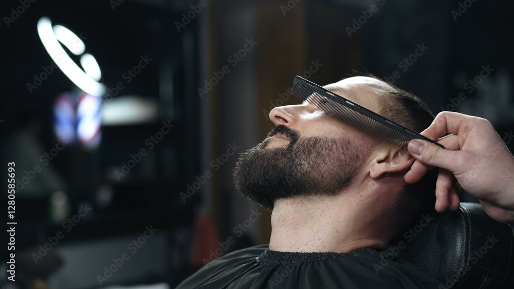 Skilled barber carefully combing thick beard of male client, providing professional grooming service in traditional barbershop setting with precision and attention to detail