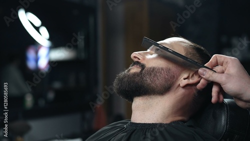 Obraz na płótnie Skilled barber carefully combing thick beard of male client, providing professional grooming service in traditional barbershop setting with precision and attention to detail w salonie