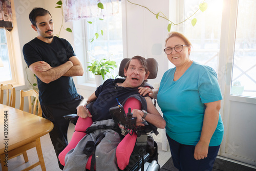 Portrait of happy female caregiver standing beside man with cerebral palsy sitting on wheelchair