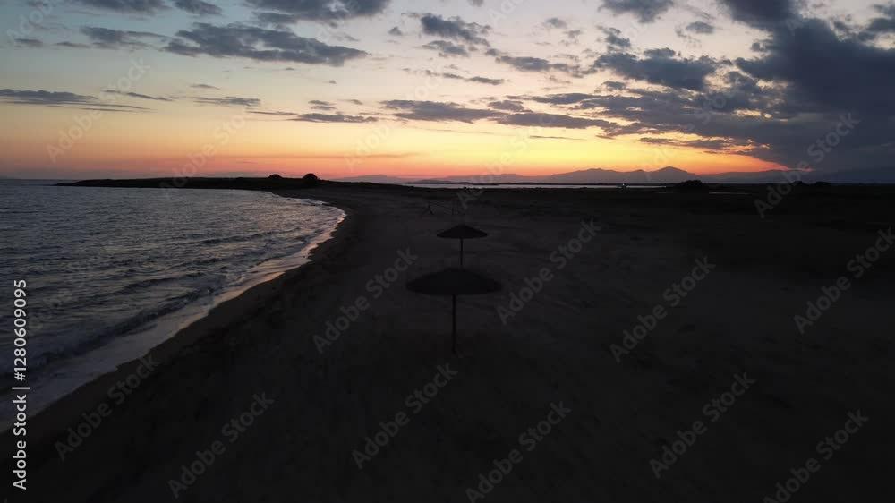 Golden Sunset Drone Aerial Shot of Milivoti Beach with Wicker Umbrellas, A Summer Paradise in Greece