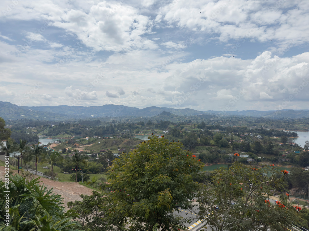 Obraz premium Scenic landscape with lush greenery, distant mountains, and a cloudy sky.