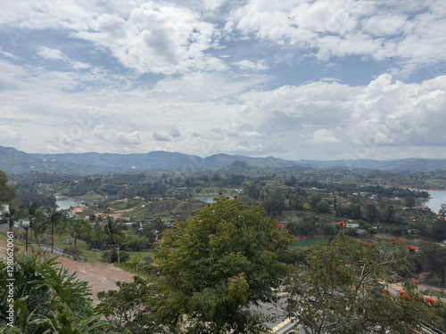 Scenic landscape with lush greenery, distant mountains, and a cloudy sky.