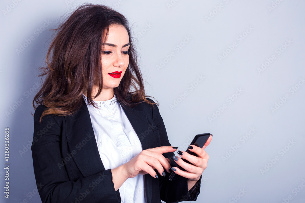 Smiling businesswoman using smartphone on gray background Smiling businesswoman using smartphone on gray background