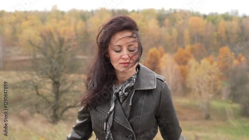 Autumn landscape with gothic woman has windy hair. Stylish woman sing in autumn landscape outdoor. Fall nature landscape and girl. Central park in New York. Girl in fall trench. Feeling free