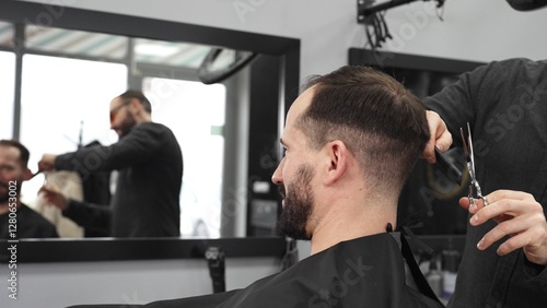Skilled barber trimming client's hair using professional scissors, creating contemporary hairstyle in modern barbershop setting with precise, professional technique.