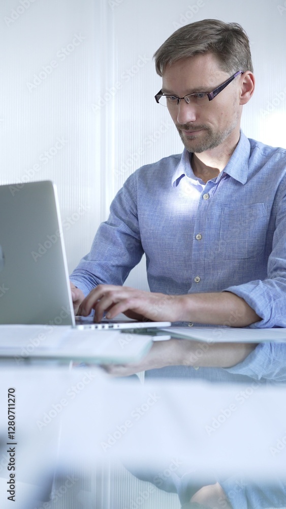 Casual dressed businessman is using a laptop in a contemporary office, with a clean, bright environment that boosts efficiency. Business people concept Casual dressed businessman is using a laptop in a contemporary office, with a clean, bright environment that boosts efficiency. Business people concept