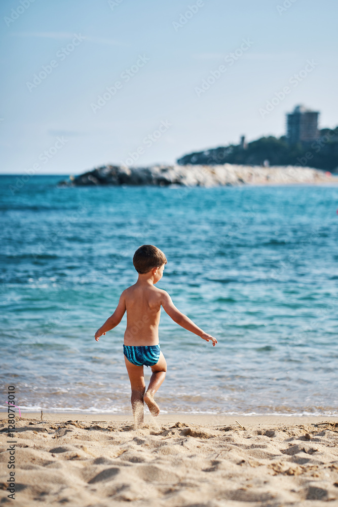 Young boy running towards the sea on a sunny beach day Young boy running towards the sea on a sunny beach day